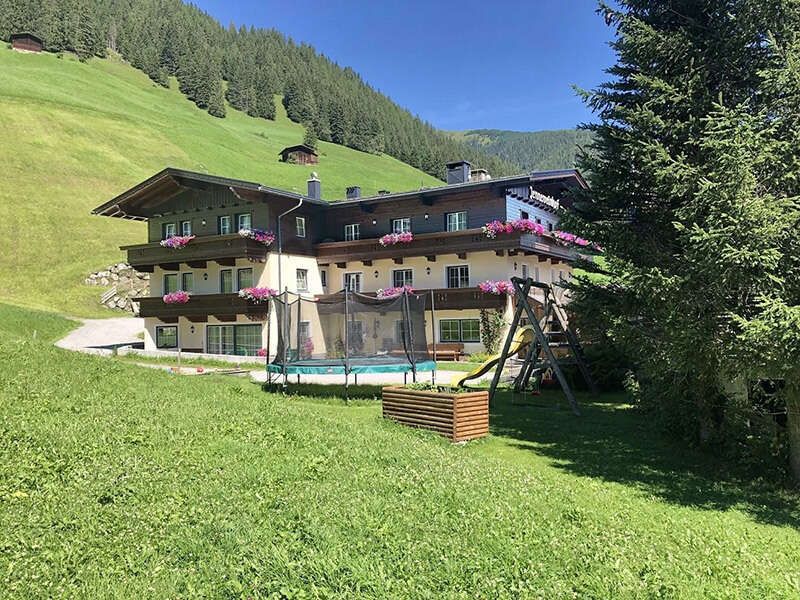 Hausansicht im Sommer mit Trampolin und Spielplatz